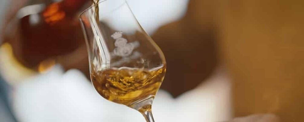 A glass of amber liquid being poured. 3