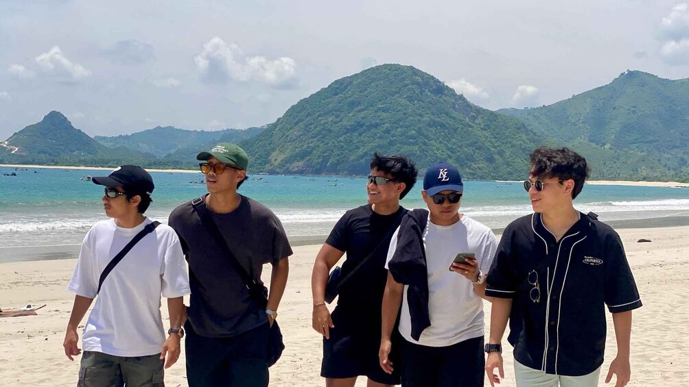 A group of people on a beach with mountains in the background. 3