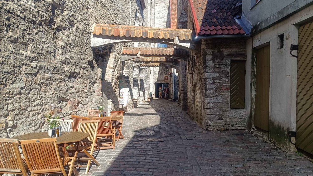 A cobblestone alley with wooden furniture and stone walls. 1