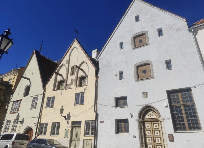 A street with historic buildings, including a building with a pointed roof and another with a large arched window. 5