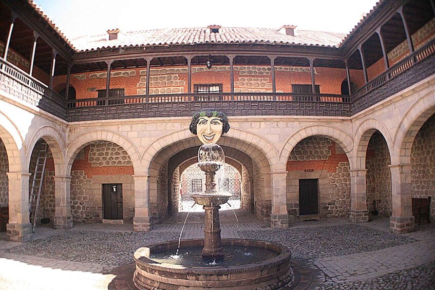 A courtyard with a fountain, arches, and a building with a tiled roof. 4