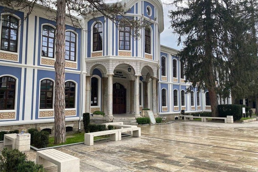 A large, historic building with blue and white exterior, arched windows, and a central entrance. 1