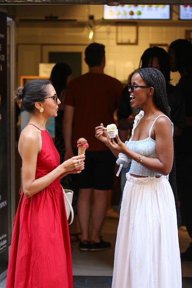 Two women holding ice cream cones in front of a food truck. 4
