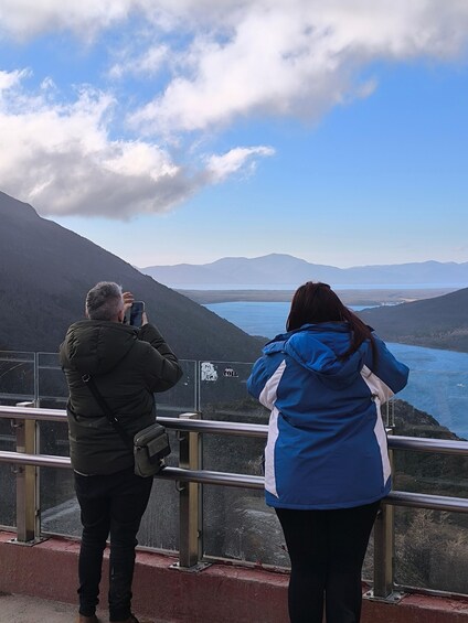 Two people taking photos of a mountainous landscape with a lake. 5