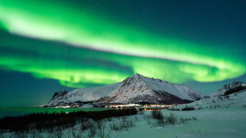 Et snøklædt bjerglandskab under et livligt grønt nordlys. 4