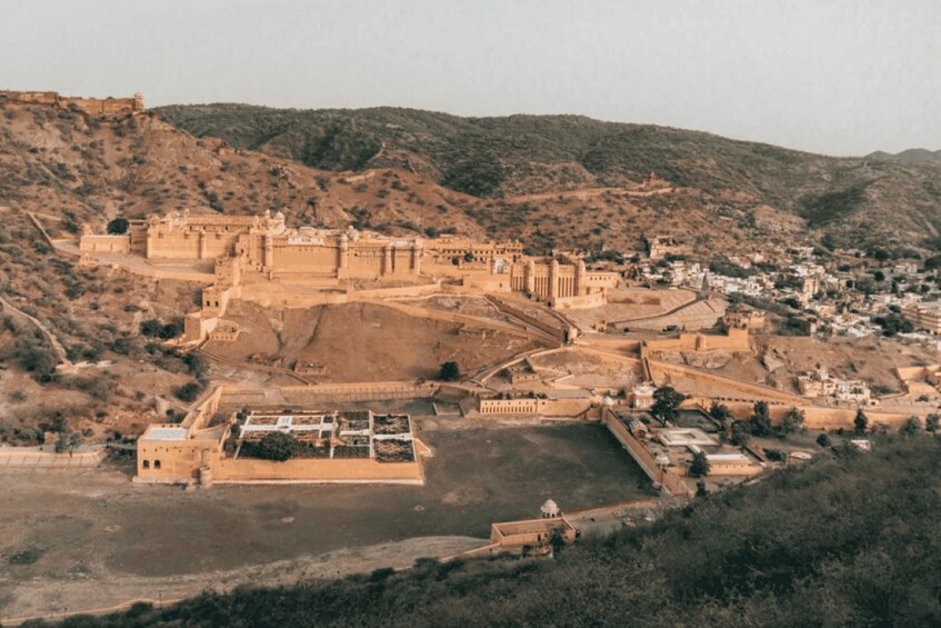 A historic fortification with a large courtyard, surrounded by hills and a small town. 2