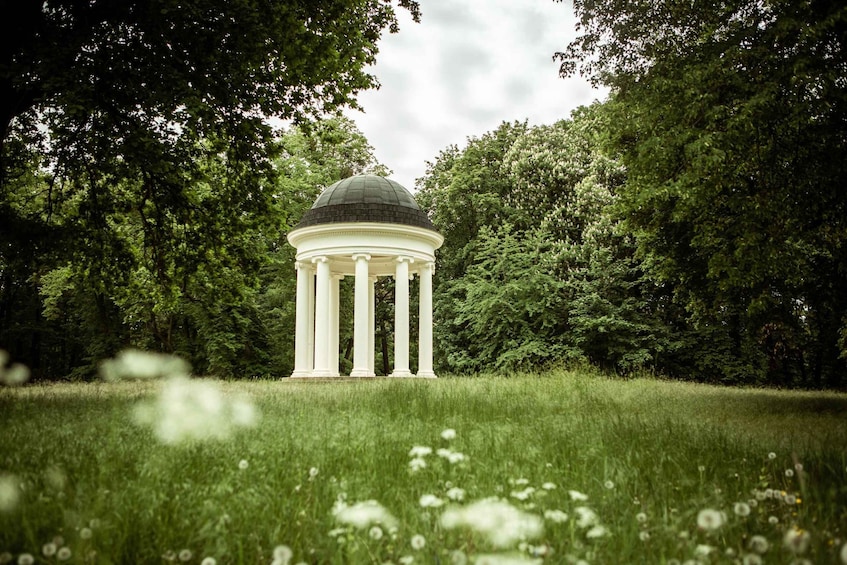 A white gazebo with a dome roof surrounded by lush greenery. 3