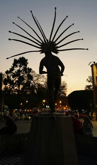 A statue with a large, star-like head, standing on a pedestal in a public square. 3