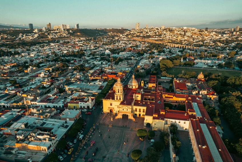An aerial view of a city with a prominent cathedral, a bridge, and dense urban development. 1