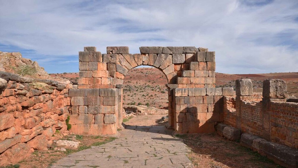 An ancient stone archway leading through a desert landscape. 2