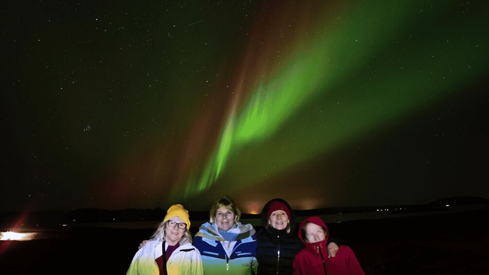A group of people standing under a night sky with visible aurora borealis. 2