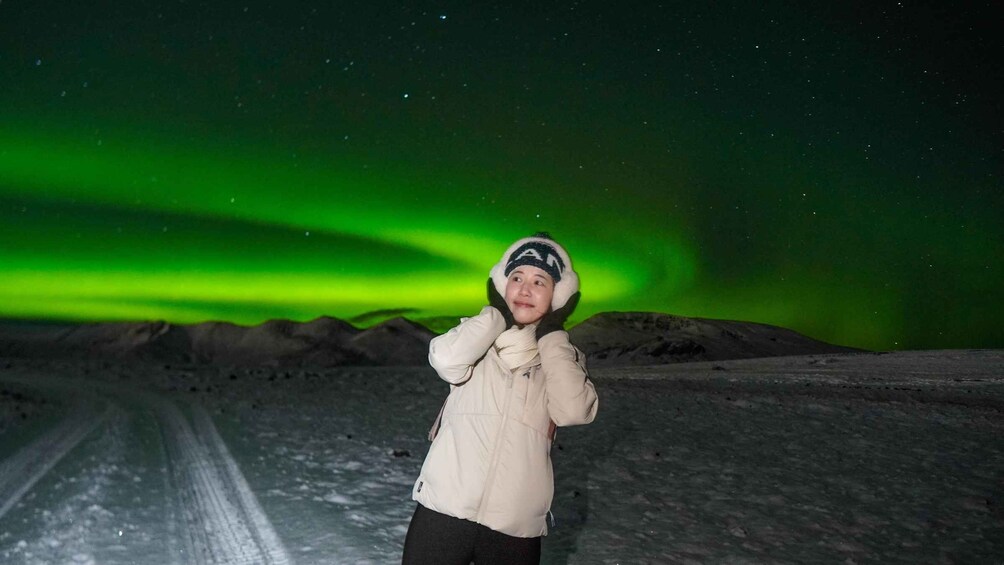 A person standing on a snowy landscape with the aurora borealis in the background. 3