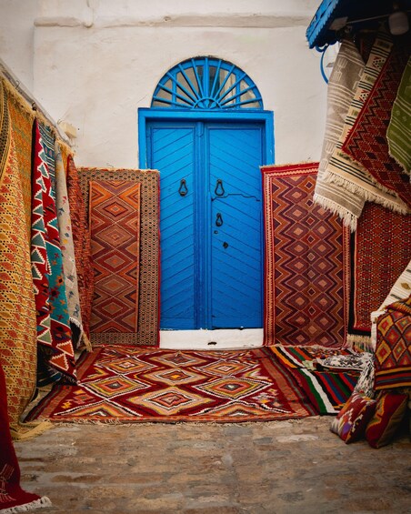 A blue door with intricate patterns, surrounded by colorful rugs and textiles. 3
