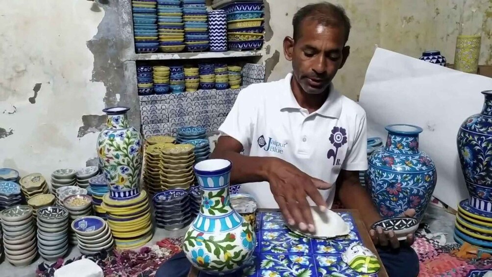 A person arranging ceramic plates and vases in a shop. 3