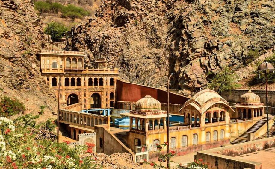 A historical building with arches and domes, situated in a rocky landscape. 1