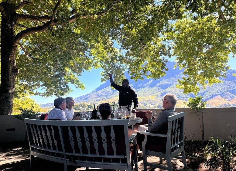 A group of people dining outdoors with a mountain view. 4