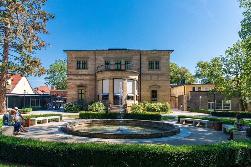 A historic building with a fountain in the courtyard surrounded by benches and greenery. 3