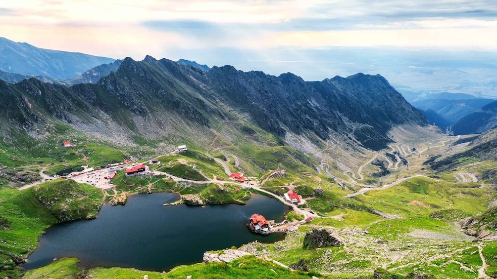A mountainous landscape with a lake, winding roads, and scattered buildings. 1