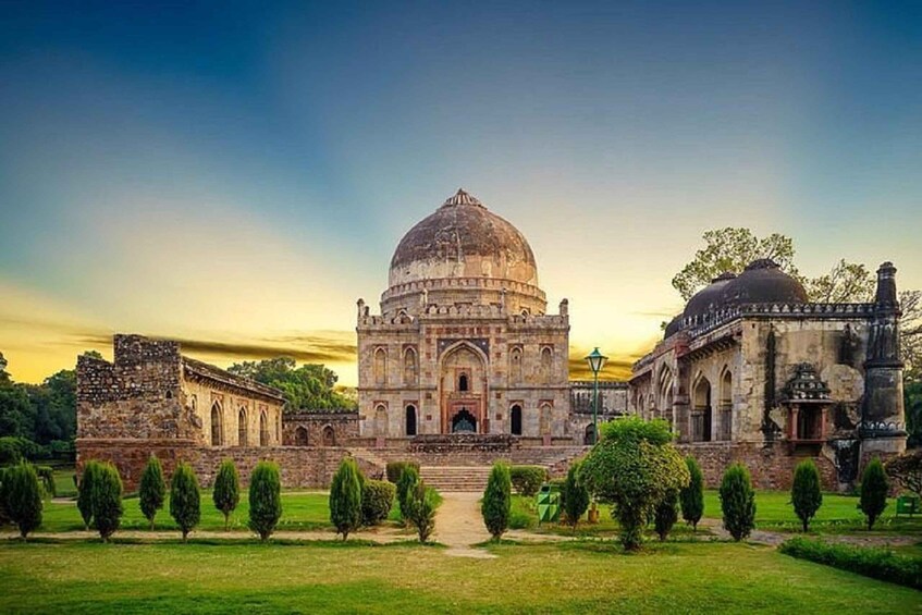 A historic building with a large dome and arched windows, surrounded by a well-maintained garden with trimmed hedges. 1