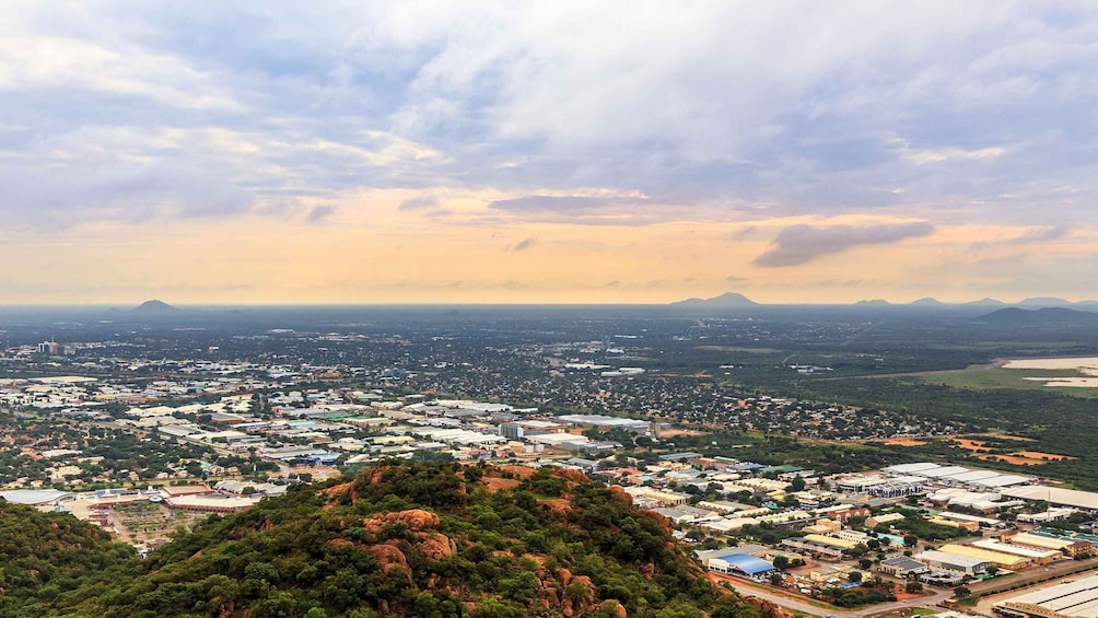 A cityscape with a mountain in the foreground and a flat terrain with buildings in the background. 3
