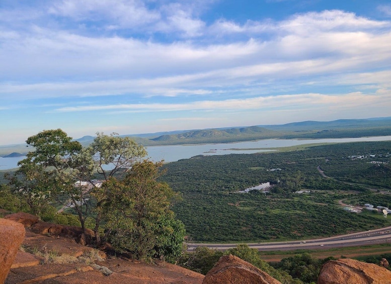 A mountainous landscape with a lake, dense greenery, and a clear sky. 2
