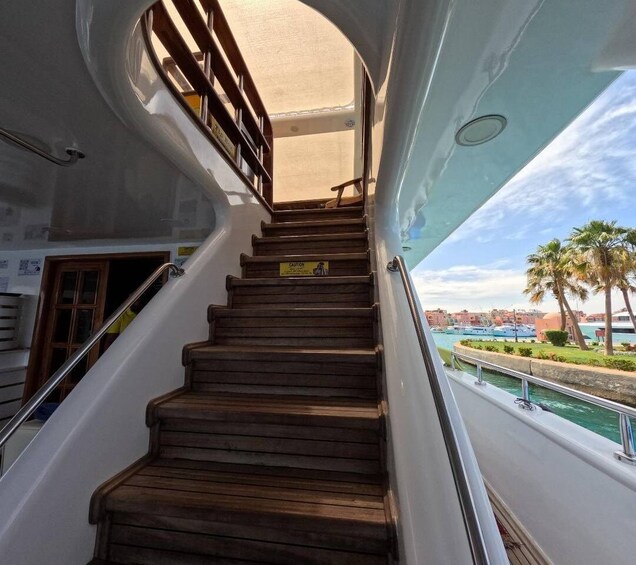 A wooden staircase on a boat with a view of a marina and palm trees. 5
