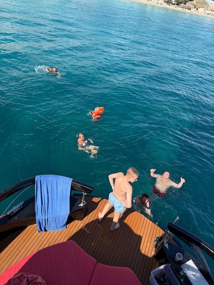 A boat deck with people swimming in the water. 5
