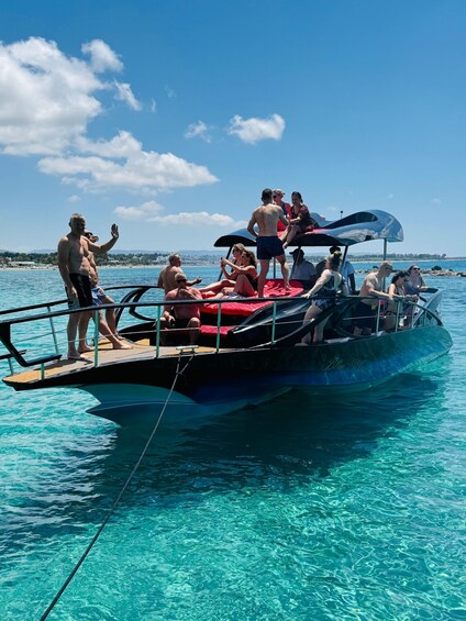 A boat with people on deck, clear blue water, and a distant shoreline. 5