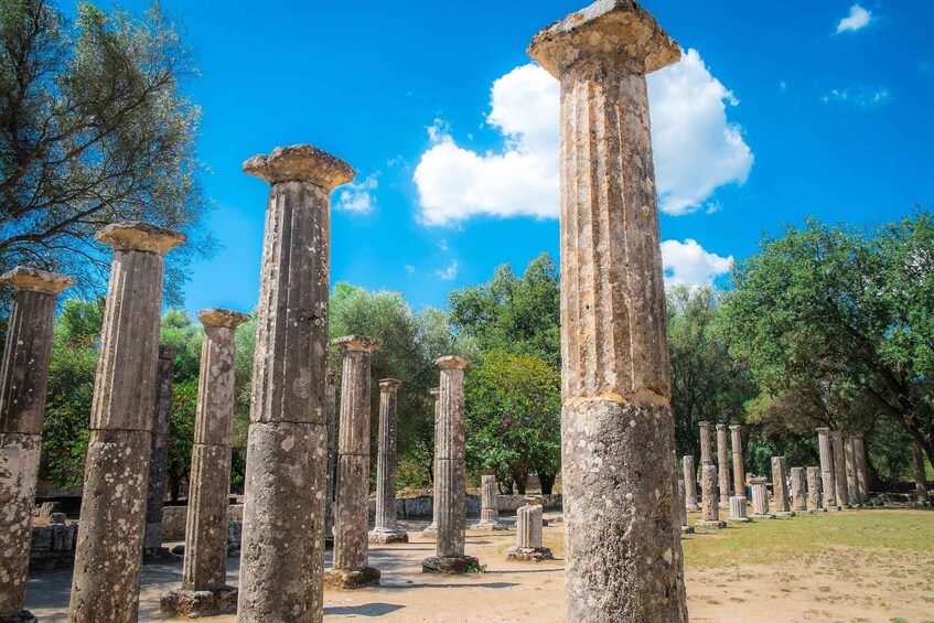 Ancient stone columns in a historical site with trees in the background. 2