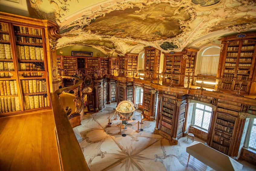 An ornate library with high ceilings, intricate woodwork, and a central globe display. 5