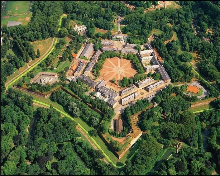An aerial view of a historic walled complex with a central courtyard, surrounded by buildings and lush greenery. 2