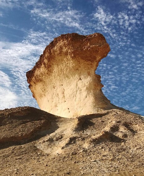 A large rock formation with a prominent overhang against a clear sky. 3
