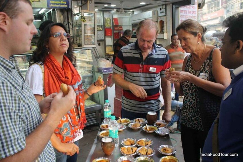 People eating at a street food stall with various dishes and drinks. 4