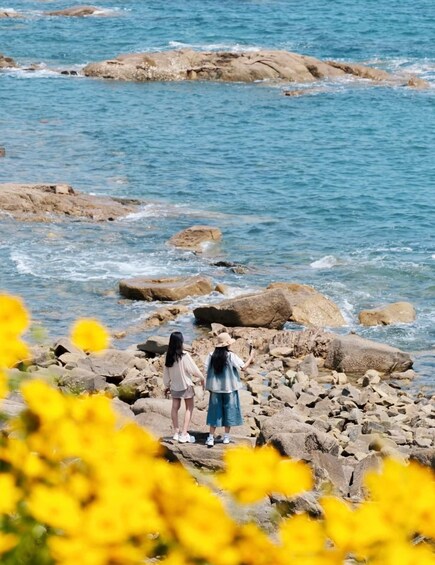 Two people standing on rocks by a body of water. 1