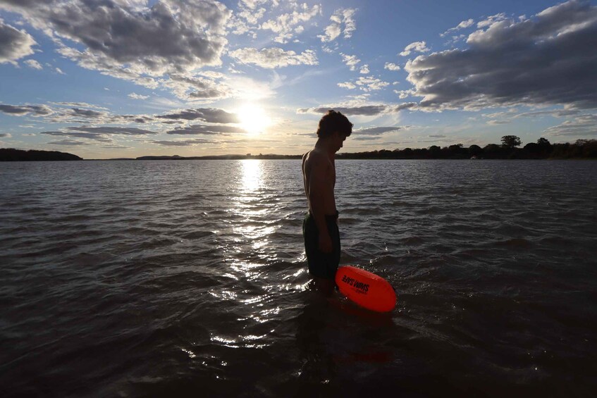 A person standing in water holding a surfboard. 2