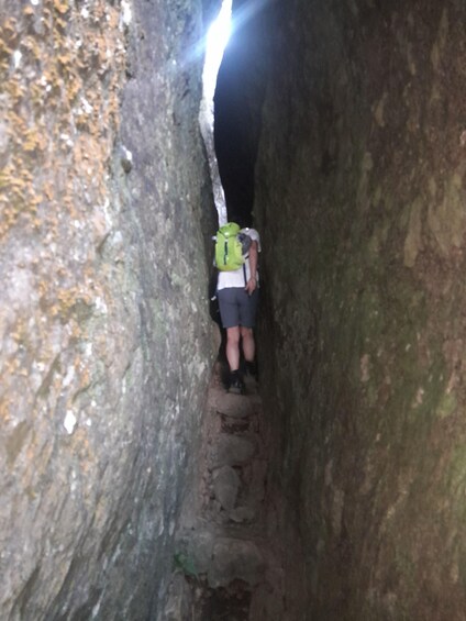 A person hiking through a narrow, rocky passageway. 3