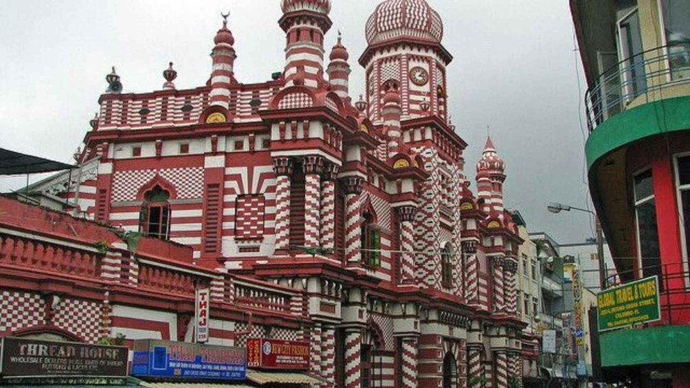 A building with intricate red and white patterns, domed towers, and a clock. 2