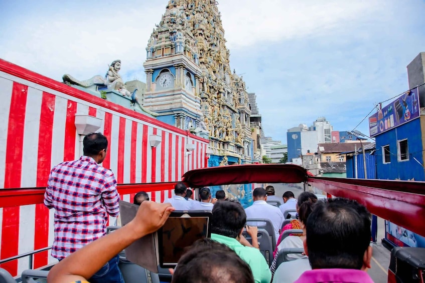 A group of people on a bus with a large, ornate temple in the background. 4