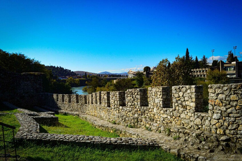 A stone wall, a river, and buildings in the background. 5