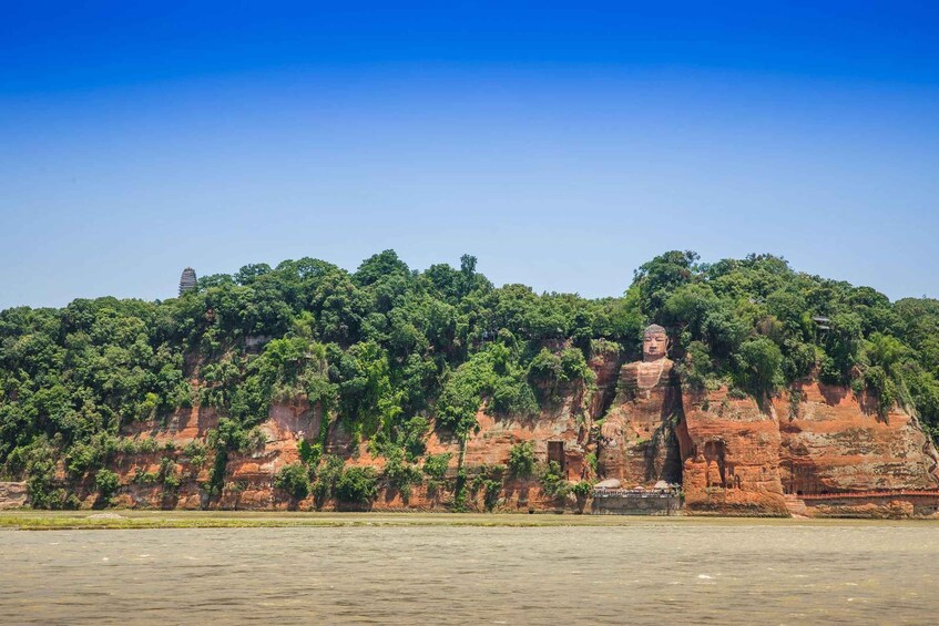 A large Buddha statue on a cliff, surrounded by lush greenery and a river. 2