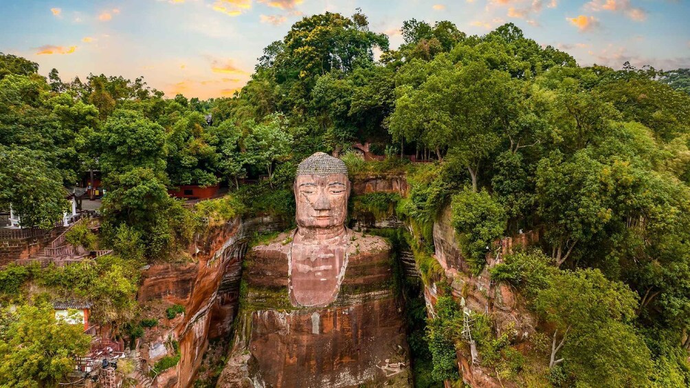 A large Buddha statue carved into a cliff, surrounded by lush greenery and a temple complex. 3