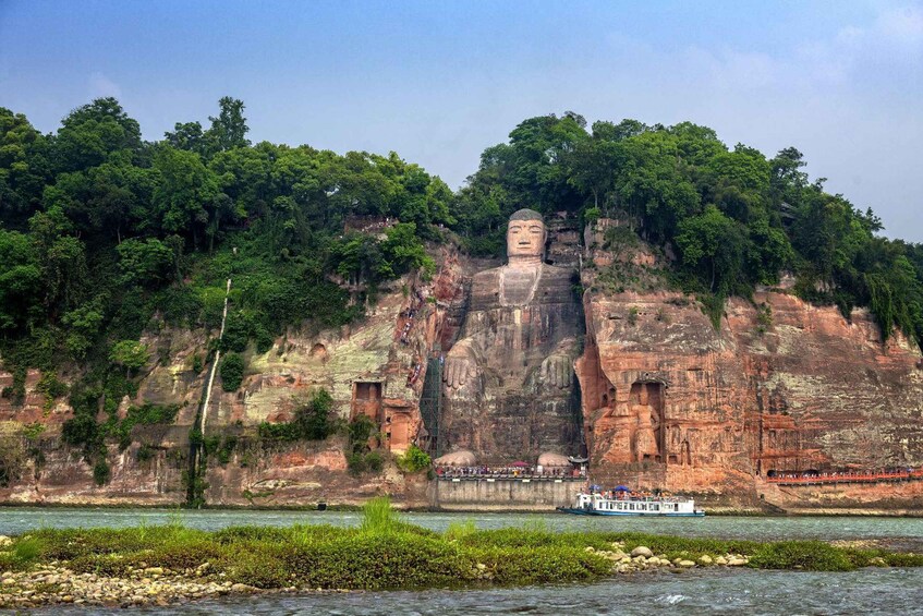 A large Buddha statue on a cliff by a river. 5