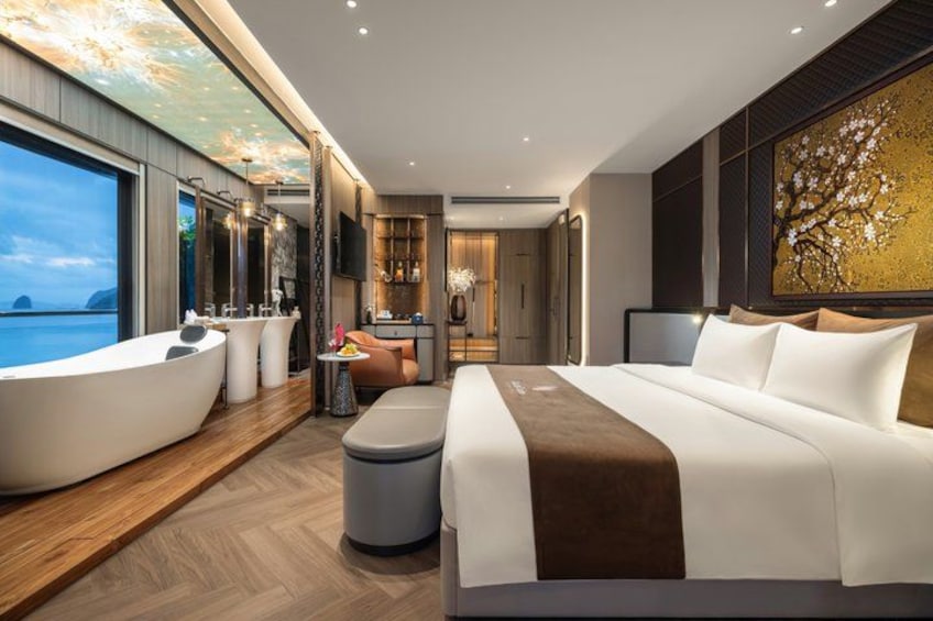 A modern bedroom with a large bed, a bathtub, and a view of the ocean. 1