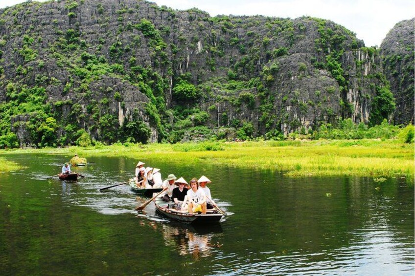 A group of people in a boat on a river, surrounded by lush greenery and rocky cliffs. 3