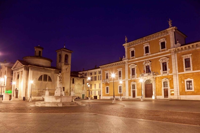 A historic square with a fountain, a church, and classical buildings at night. 5