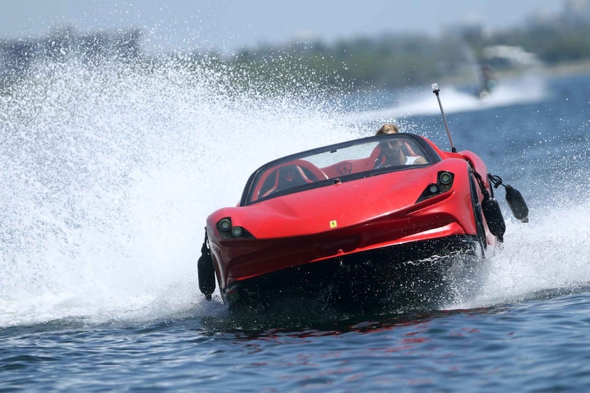 Un'auto sportiva rossa che sfreccia sull'acqua, sollevando un'onda alta. 5