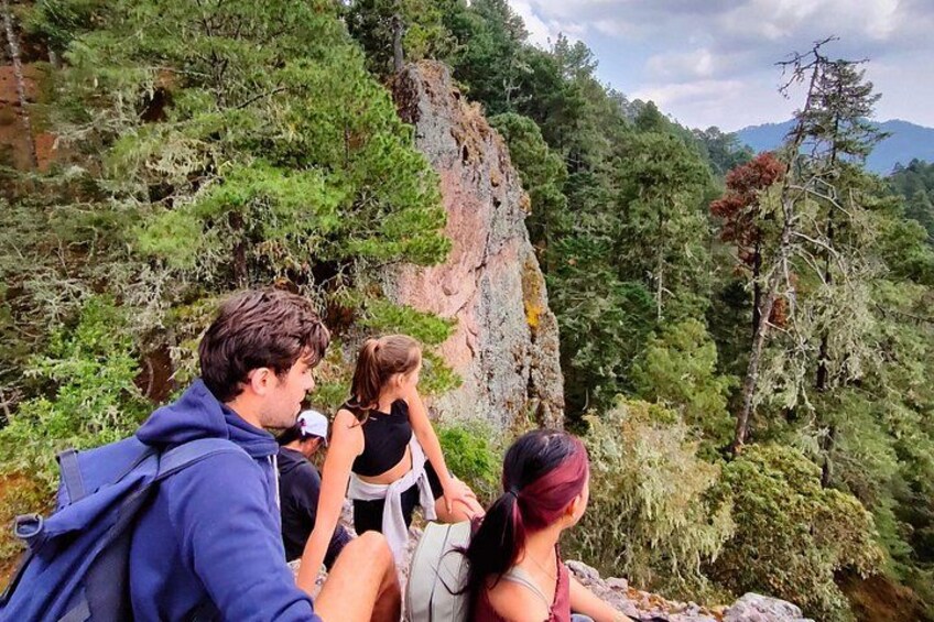 A group of people hiking on a rocky trail surrounded by dense forest and mountains. 2