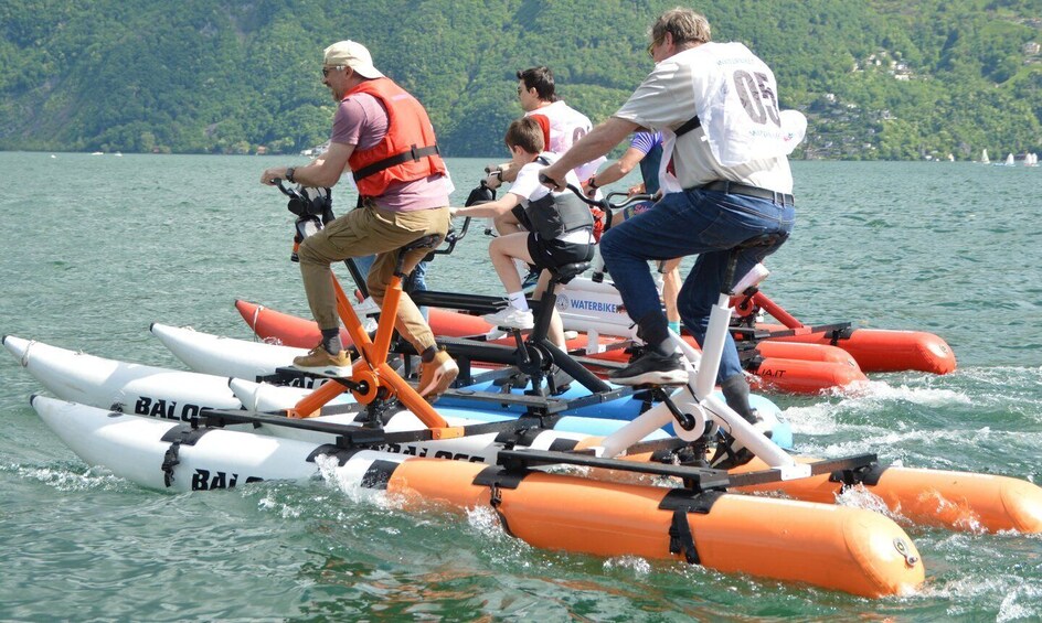 People riding water bikes on a lake with boats in the background. 1