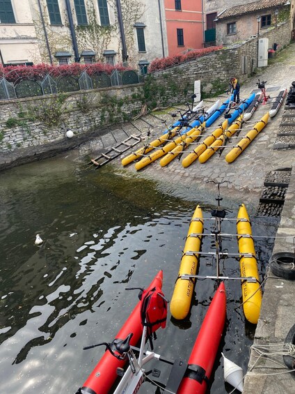 A waterway with yellow and red watercraft, a stone wall, and buildings in the background. 2