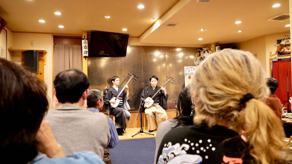 A group of musicians performing in a room with an audience. 4